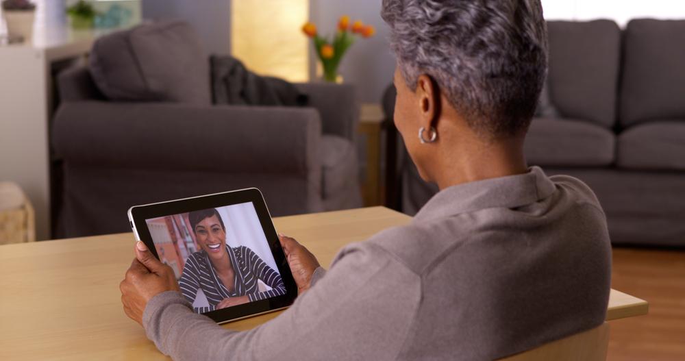 Woman holding a tablet having a video call with another woman.